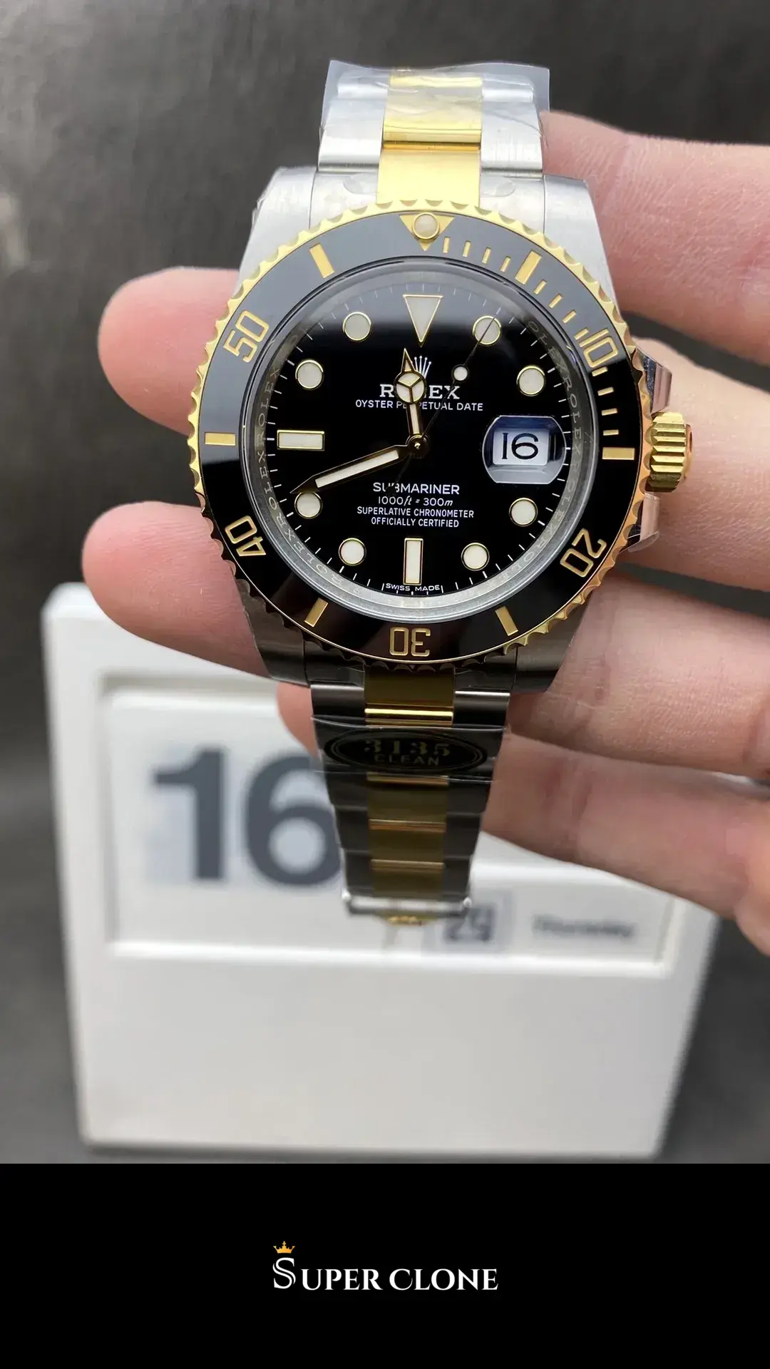 Full watch held upright in bare fingers, date window reading sixteen
